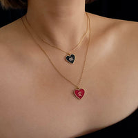 Two heart-shaped pendants on gold necklaces against a neutral background