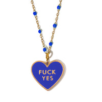 A necklace with a heart-shaped pendant that has the phrase 'FUCK YES' enamelled on the front, and 'NO THANKS' embossed on the back, with blue enamel detailing on the pendant, attached to an 18k gold plated chain.