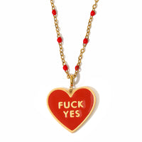 A red and gold-colored necklace with a heart-shaped pendant that reads 'FUCK YES' in bold letters.