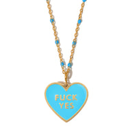 A necklace with a heart-shaped pendant that has the phrase 'FUCK YES' written on it in yellow enamel, attached to a gold-plated chain.
