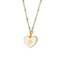 A white heart-shaped pendant necklace with a gold-plated chain and blue bead accents, displayed against a white background.
