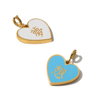 A reversible heart-shaped pendant with one side white and the other cyan, both featuring Chinese characters DREAM DESIRE, attached to a gold-plated clasp.
