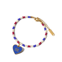 A gold-plated stainless steel bracelet with red, white, and blue beads and a blue heart-shaped pendant with the text 'LOVE' on it.