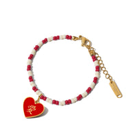A gold-plated stainless steel bracelet with red and white beads and a red heart pendant, featuring Chinese characters.