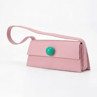 Pink handbag with a green button on a white background