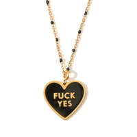 A black heart-shaped pendant necklace with the phrase 'FUCK YES' written in white on the front, attached to a gold-colored chain.