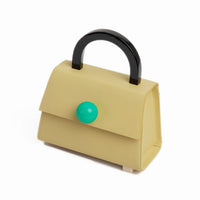 An olive green satchel bag with a resin handle and asymmetric resin studs at the bottom. It features a removable shoulder strap and a green sphere on top.