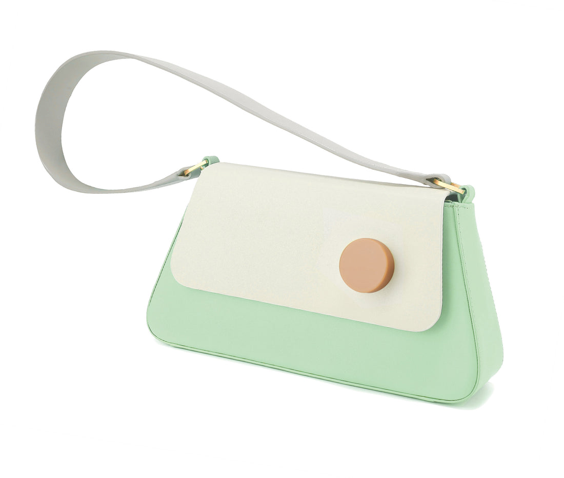 A light mint green and white flap shoulder bag with a wide strap and a leather shoulder strap, featuring a matt gold D ring and resin stud.