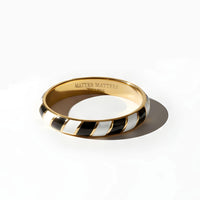 Gold enamel ring with black and white striped Memphis design on a white background